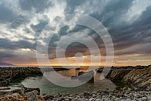 Beautiful sunset on a glass beach by the sea surrounding Sicily and its rocky shores