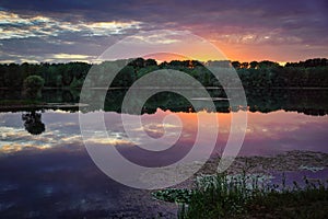 A beautiful sunset at a lake. Orange and purple clouds reflecting in the water. Germany, Baden-Wuerttemberg