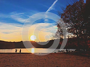 Beautiful sunset by the lake and trees silhouette