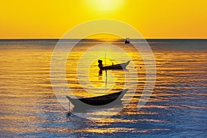 Beautiful sunset landscape, yellow sky, golden sun glow reflection on water, fisherman boats silhouette on blue sea background