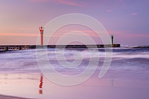 sunset with lighthouse and blue clouds over the sea