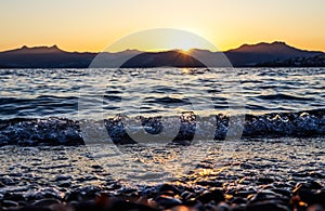 Beautiful sunset on the Mediterranean coast with islands and mountains. Stones on the beach lit by sunlight