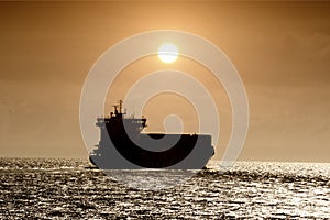 Sunset and containership sailing in open waters photo