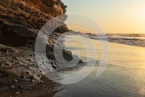 Beautiful sunset on the Namibe wild beach, Africa. Angola. With cliff and rocks