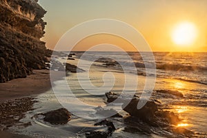 Beautiful sunset on the Namibe wild beach, Africa. Angola. With cliff and rocks