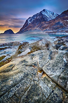 Beautiful sunset Norway landscape of picturesque stones on the arctic beach of cold Norwegian Sea