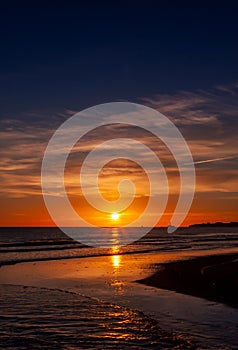 The beautiful sunset, orange blue sky and clouds over the Blyth Beach. St. Mary`s Lighthouse and Seaton Sluice village