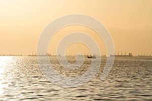 Beautiful sunset orange sky with cargo ship and fisherman boat.