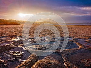 Beautiful sunset over beach in Swinoujscie near Baltic sea with stones and puddles