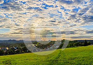 Beautiful sunset over countryside landscape of rolling hills with sun beams piercing sky and lighting hillside