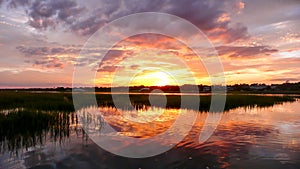 Beautiful sunset over marsh grass and coastal ocean waters at high tide with forest in the background