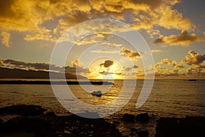 Beautiful Sunset over the ocean along rocky shore