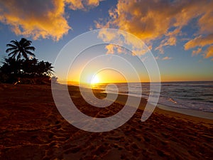 Beautiful Sunset over the ocean and beach with waves moving to shore and foot prints in the sand