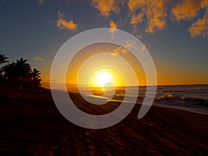 Beautiful Sunset over the ocean and beach with waves moving to shore and foot prints in the sand