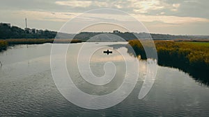 Beautiful sunset over river with small waves and reeds. Sun breaks through clouds at evening. Recreation and hobbies at