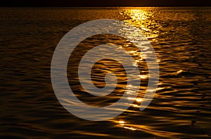 Beautiful sunset over the river. The solar path on the surface of the water. Reflection of the setting sun