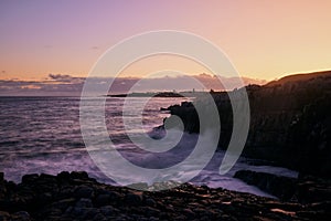 Beautiful sunset over a rocky coast, with waves crashing against the shore. Hermanus, Western Cape.