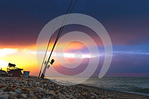Beautiful sunset over the sea. Fishing rods on the shore of the sea against the background of a dramatic sunset.