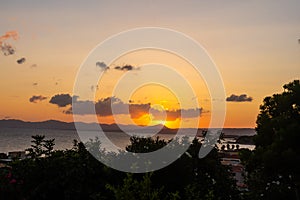 Beautiful sunset over the sea with a view at palms on the beach