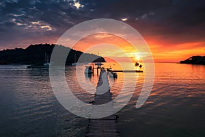 Beautiful sunset over tropical sea and wooden pier, sightseeing boat and tourist enjoying in Koh Kood Island