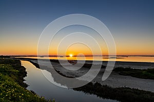 Sunset over wetlands and marshlands with a colorful sky and a sun star on the horizon