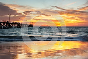 A beautiful sunset at Port Noarlunga with the jetty and sunset reflections on the sand at Port Noarlunga South Australia on 18th