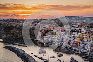 Beautiful sunset at Procida island. Sun setting behind the colorful houses of Corricella port, Italy