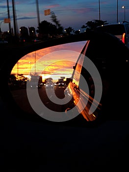 Beautiful sunset through the rear view mirror of a vehicle on the road during a vacation trip