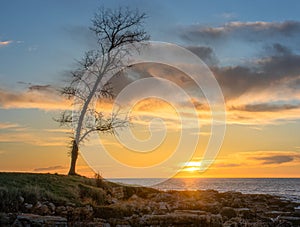 Beautiful sunset at the rocky beach with clouds illuminated with light.