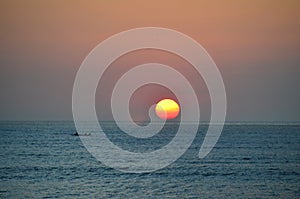 Beautiful sunset with a sailing boat at Jimbaran beach