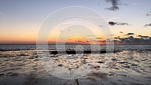 Beautiful sunset sandy beach with the colorful sky reflected on the beach and waves in the sea