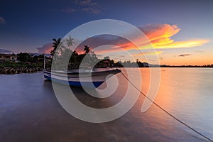 Beautiful sunset scene with fisherman boat and wooden