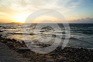 Beautiful sunset scenic copyspace wavy seaview and natural rock beach with beautiful shades of orange and blue sky background