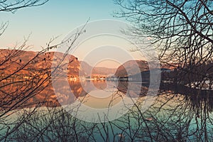 Beautiful sunset scenic image of Lake Bohinj and old Slovenian village Stara Fuzina in background seen through branches of photo