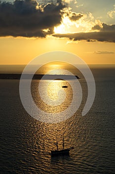 Beautiful sunset scenic ocean view in vast Aegean sea with sailing ship silhouette, abstract cloud and light reflection