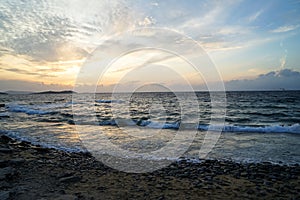 Beautiful sunset scenic wavy seaview and natural rock beach with beautiful shades of soft orange and blue sky and abstract cloud