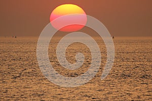 A beautiful sunset at sea with a big sun above the water