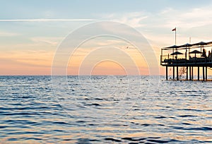 beautiful sunset on the sea. pier with umbrellas and sunbeds for vacationers