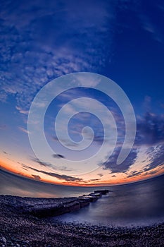 Beautiful sunset on the sea shore with a stone pontoon in the foreground on the Samothrace Island in Greece