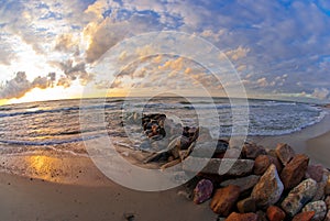 Beautiful sunset at the sea, strip of breakwaters and stones