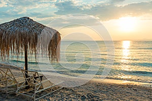 Beautiful sunset seascape with beach chairs and umbrella on the coast