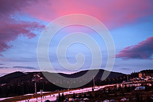 Beautiful sunset on ski resort. Purple clouds in the sky. Evening in the mountains. Ski slope and lift