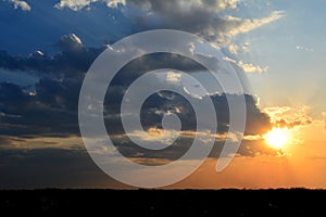 Beautiful sunset sky with dramatic light. Cloudscape with dark clouds and sun