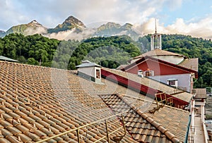 Beautiful sunset summer landscape of mountain forest and peaks seen over a hotel roof of Gorky Gorod mountain ski resort