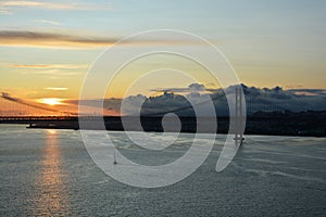 Beautiful sunset. Tejo river. 25th April bridge. Lisbon. Portugal. Almada. Clouds. Yacht. Boat. Sun. Colourfully. Light. Sunlight.