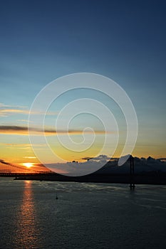 Beautiful sunset. Tejo river. 25th April bridge. Lisbon. Portugal. Almada. Clouds. Yacht. Boat. Sun. Colourfully. Light. Sunlight.