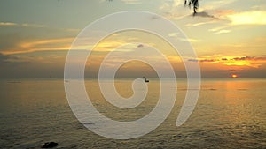 Beautiful sunset on a tropical island. The small boat with the fisherman at sunset. View from the coast. An umbrella