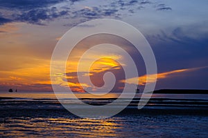 Beautiful sunset view on the beach. Colorful sea beach sunset with golden light reflected on the water surface and soft waves.