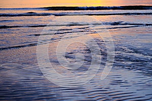 Beautiful sunset view on the beach. Colorful sea beach sunset with golden light reflected on the water surface and soft waves.