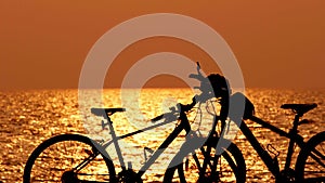 Beautiful sunset view behind mtb, mountain bike, bicycle silhouette near ocean and beach with helmet for exercise outside in